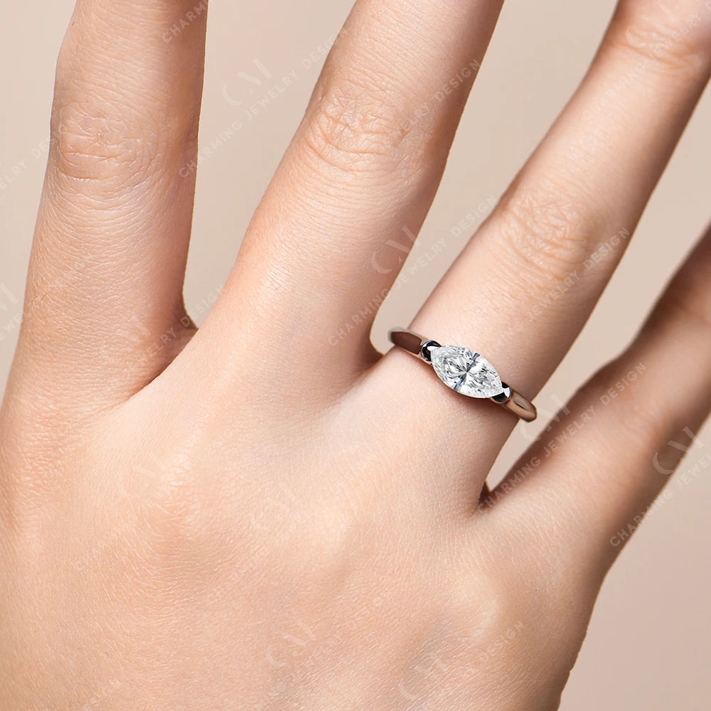 Hand wearing a diamond ring on a beige background