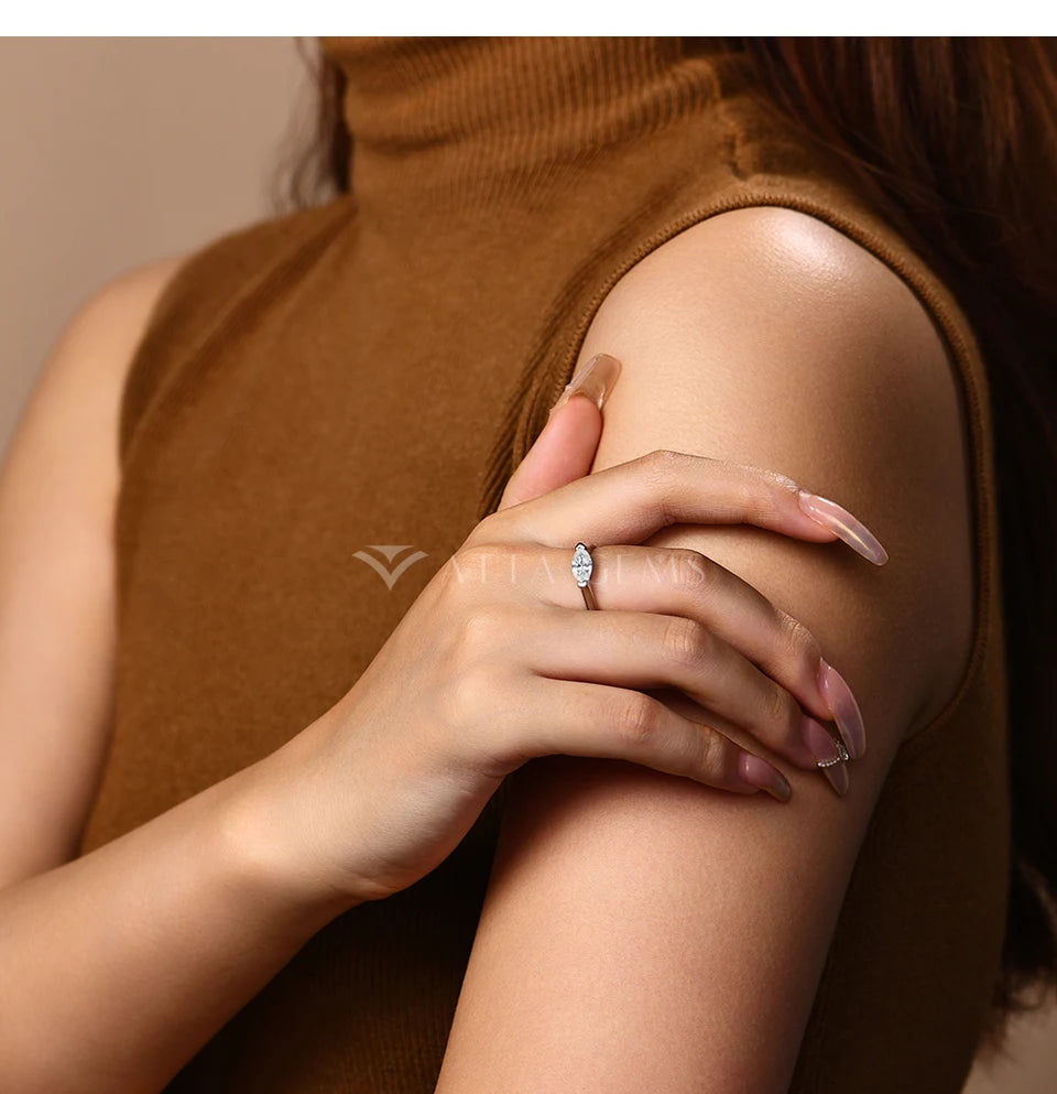 Woman wearing a sleeveless brown top with a close-up of her hand and arm, featuring a ring.